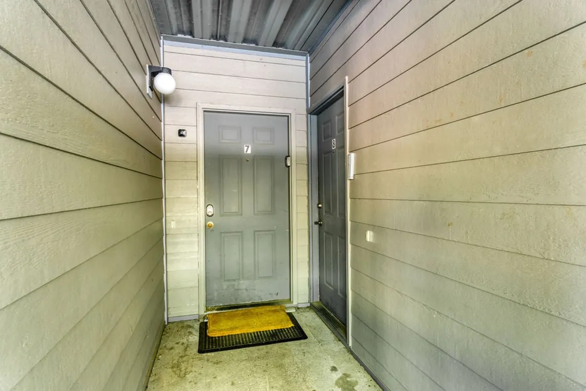 A close-up of the condo's front door with a welcoming doormat and gentle lighting, inviting guests to step inside after a day of exploring Branson. The entryway suggests comfort and the feeling of coming home to a restful retreat after enjoying local attractions.