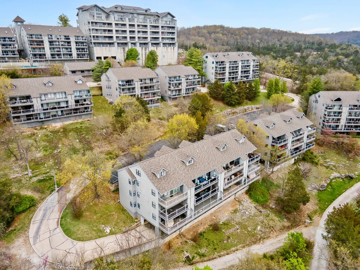This image captures the exterior of multi-level buildings surrounded by lush greenery and a winding path, inviting guests to explore the community and natural surroundings. The balconies suggest opportunities to enjoy outdoor views and sunset moments, while the landscaping hints at a tranquil neighborhood setting.